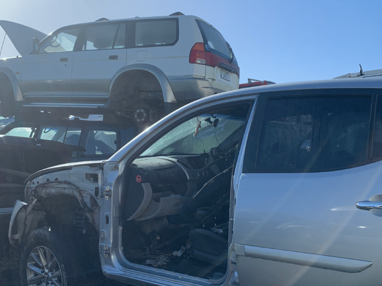 A wrecked car in a salvage yard, showcasing the services of Car Wreckers Morrinsville by Atlas Auto.